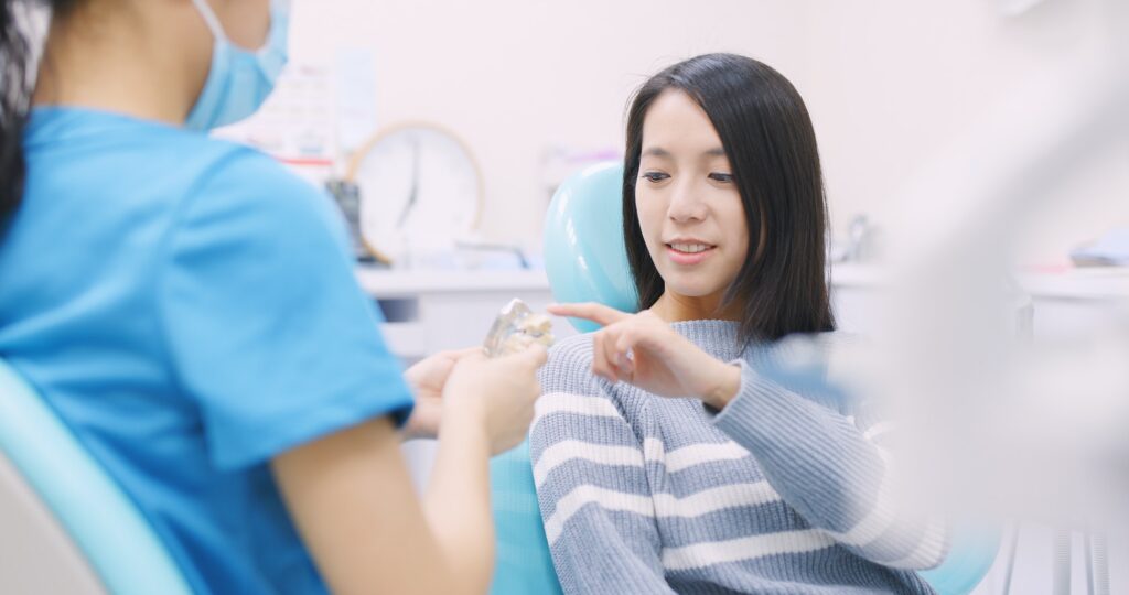 Dentist showing a patient a model of a dental implant at the chairside
