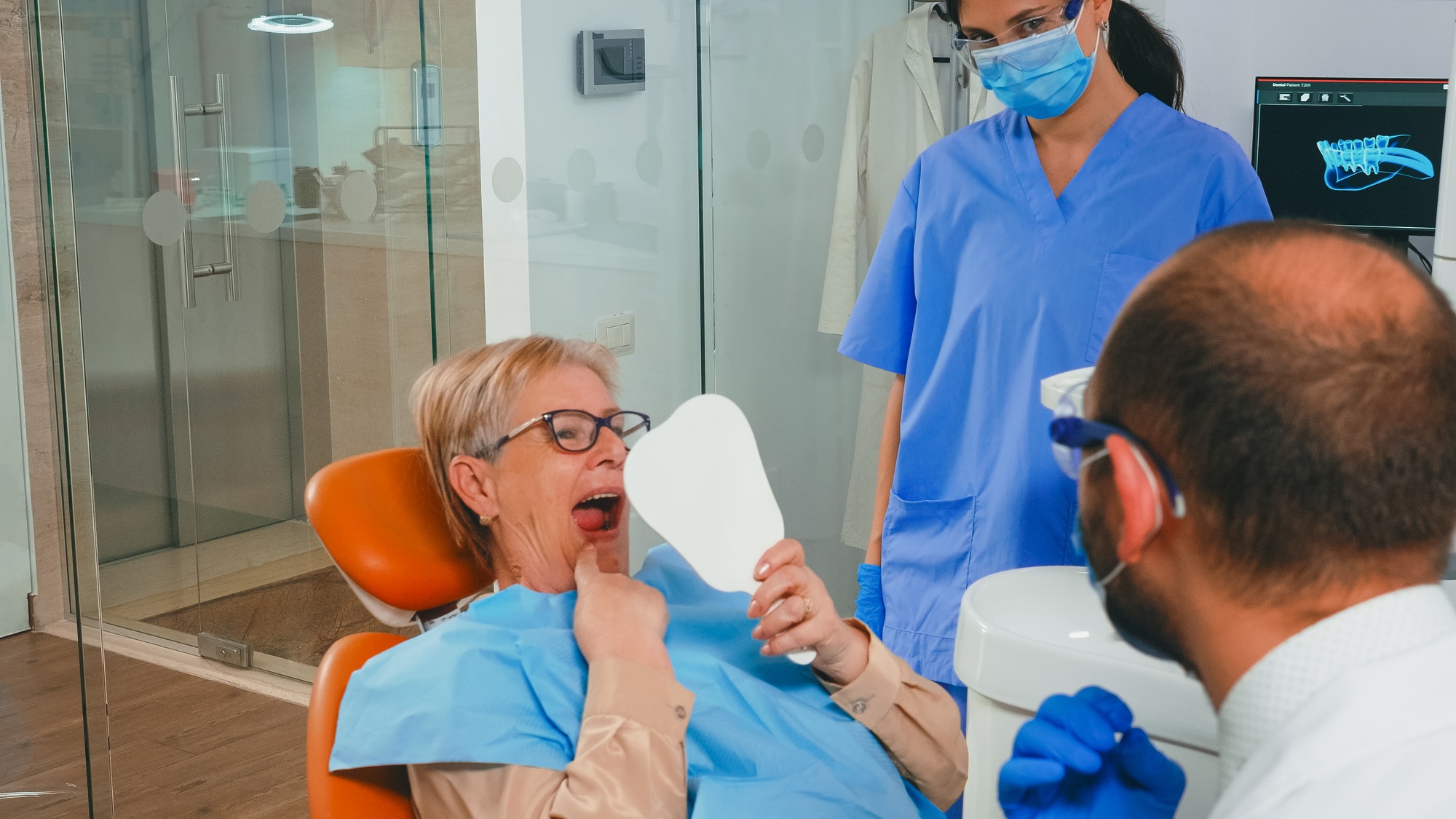 Patient checking her teeth in a hand mirror in the dental chair